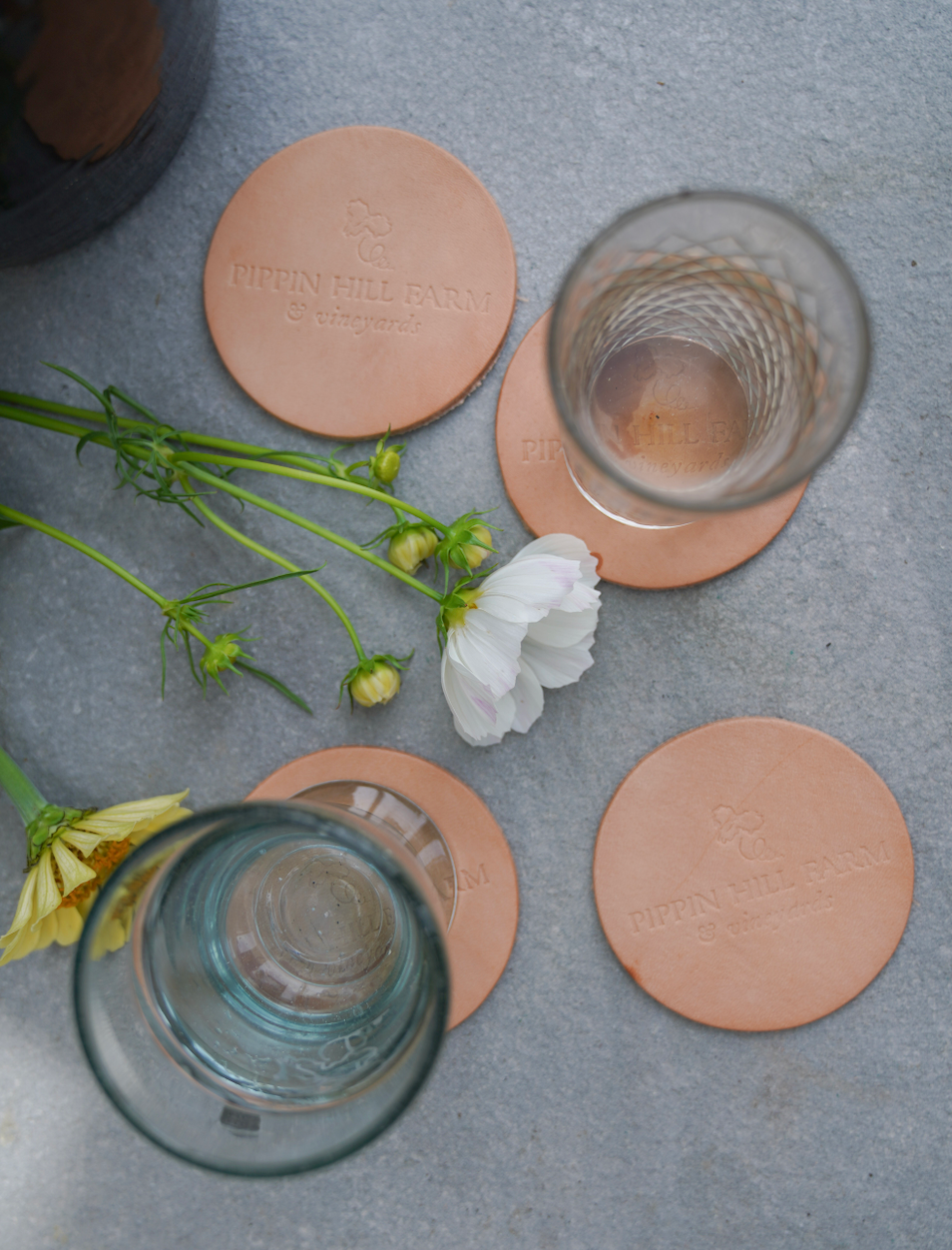 Pippin Hill branded Leather Coaster Set from Son of a Sailor. Cups are on two of the coasters. Four coasters total.