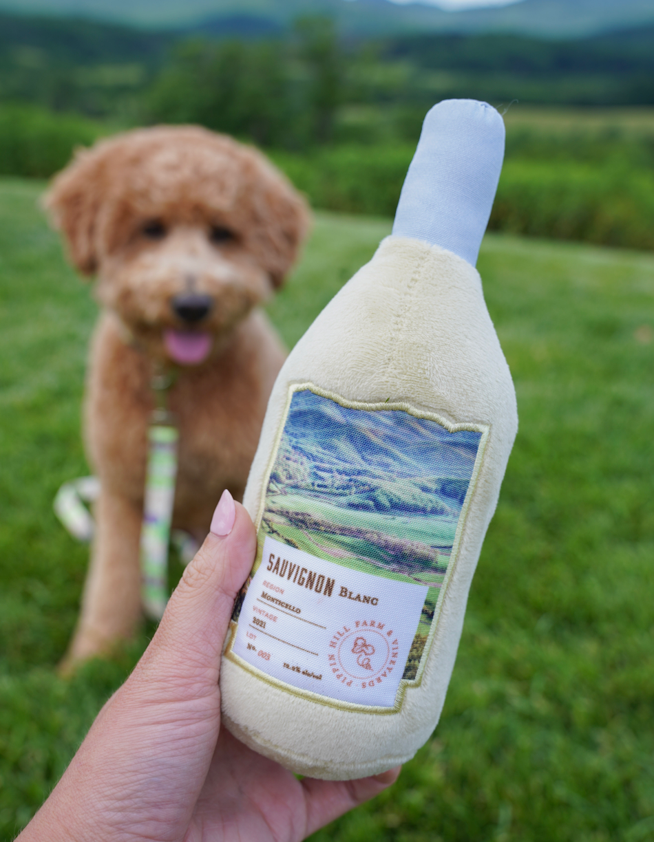 Pippin Hill Sauvignon Blanc Bottle Dog Toy in front of blurred dog in background.